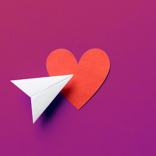 Paper plane with red heart shape on blue background. Sharing and send concept.