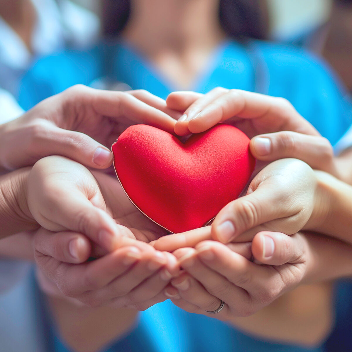 A medical team of doctors and nurses hands holding heart symboli